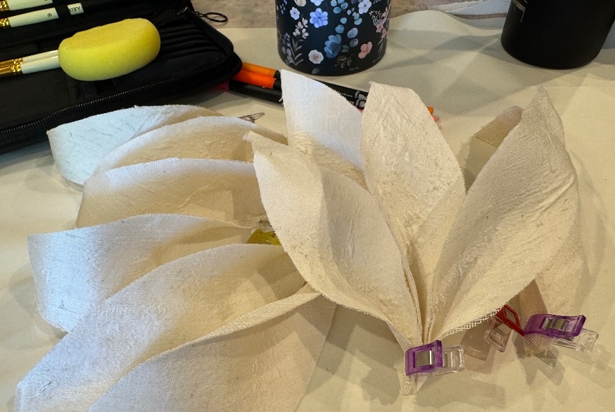 White silk petals bunched in a flower shape, before being hand painted.