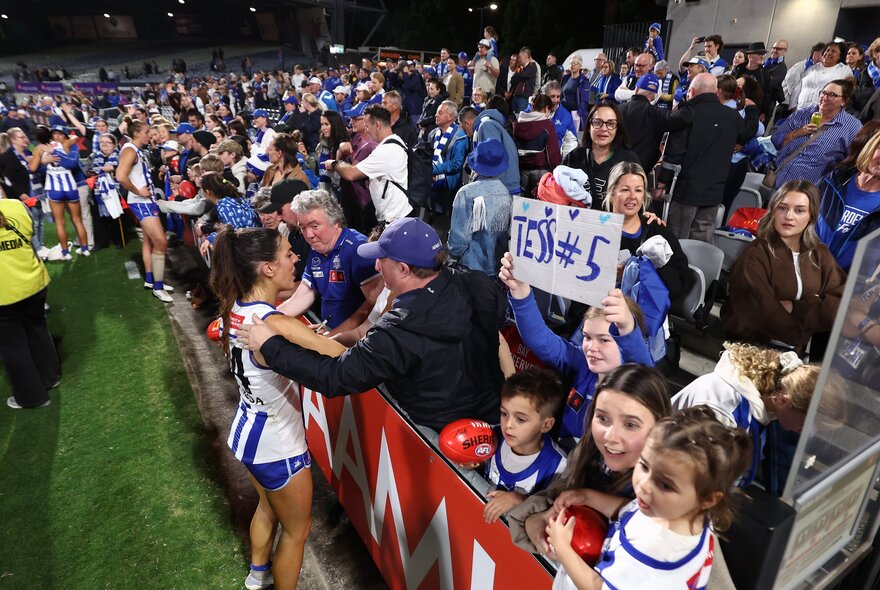 North Melboune AFLW player with fans in the stands.
