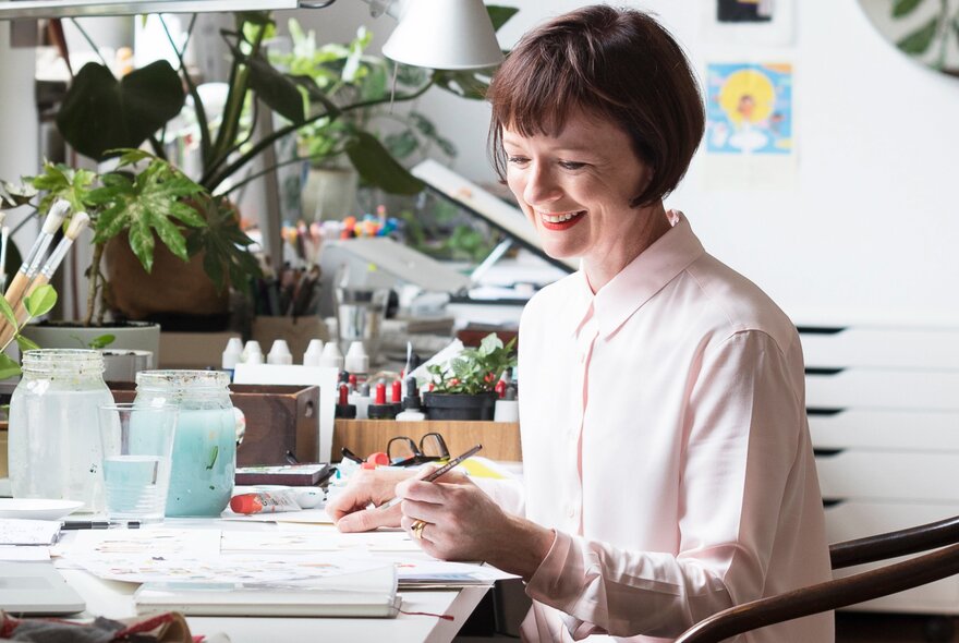 Portrait of childrens' author and illustrator, Anna Walker, working at her sunlit desk.