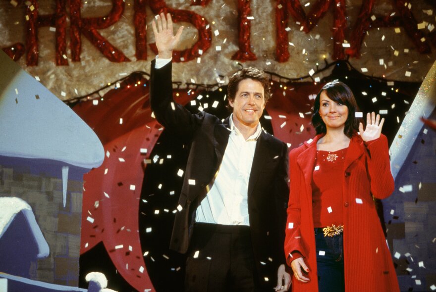 Still from Love Actually, Hugh Grant and Martine McCutcheon waving awkwardly while snow falls.