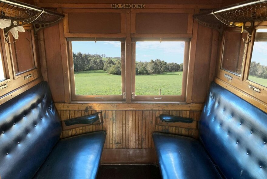 Vintage train interior with leather seats and wood panelling.