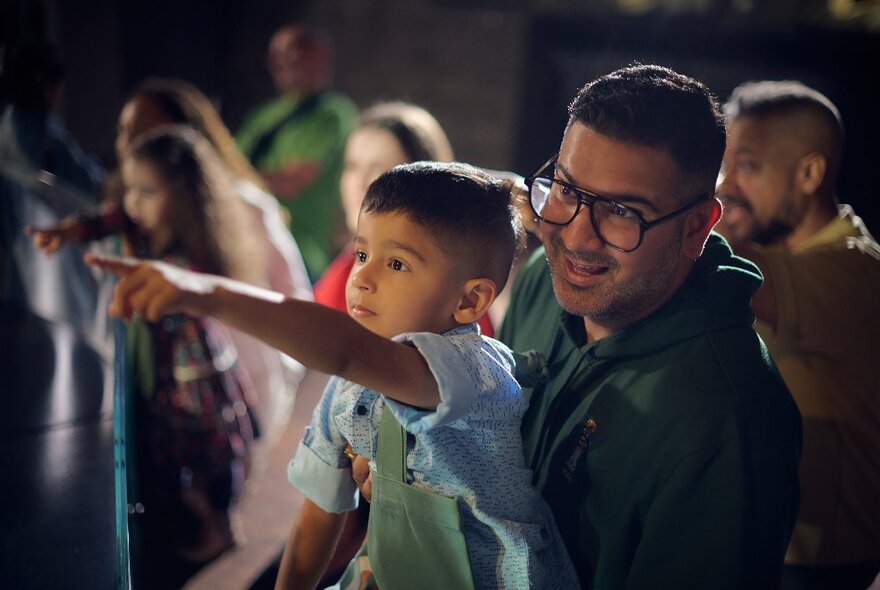 A father and his son looking at something at the Melbourne Museum, the son pointing.