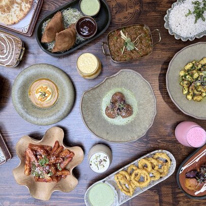 Overview of multiple Indian dishes on a wooden table.