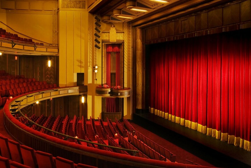 Tiered seating and red plush stage curtain.