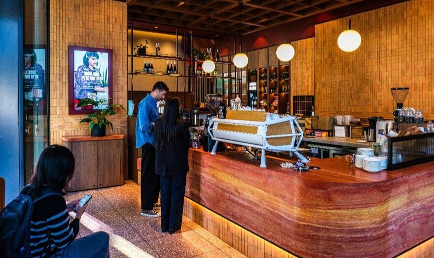 People ordering at the counter of a cafe with timber interiors.