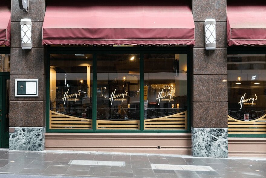 The exterior of Harry's Bar with faded red awnings and marble clad columns.