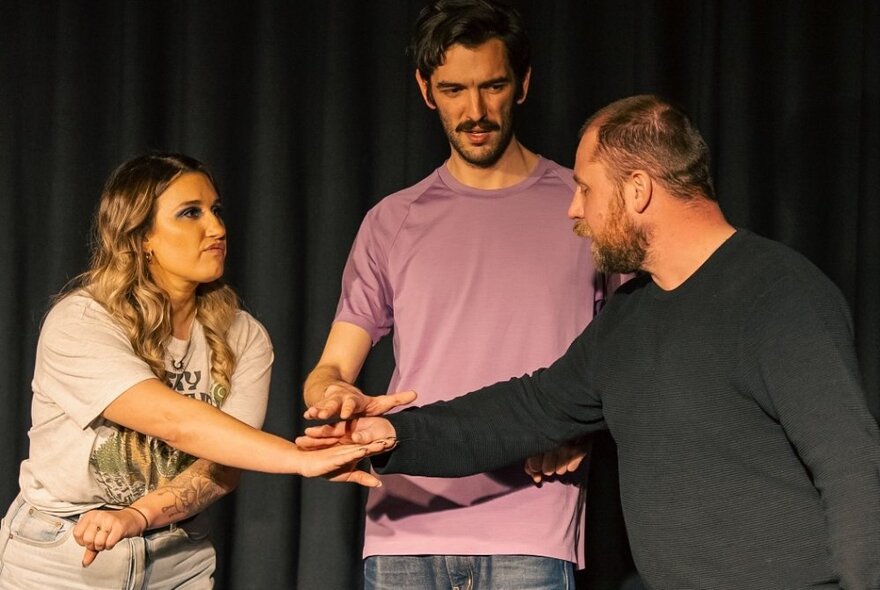 Three impro theatre performers interacting on a stage.