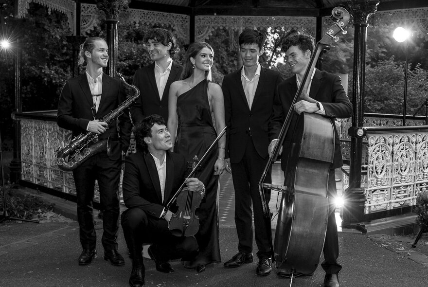 A black and white image of a string quartet posting in front of a rotunda at night. 