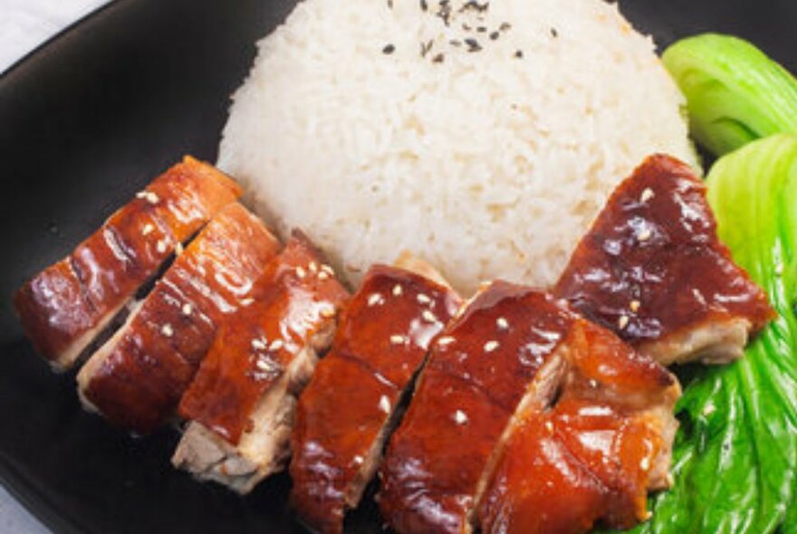 Sliced roast duck served with a ball of white rice with bok choy on the side.