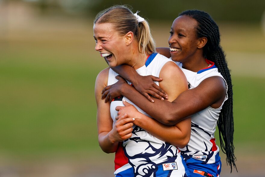 Two Western Bulldogs AFLW players celebrating and hugging on the field.