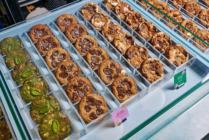 A display case under glass with neat rows of chunky cookies for sale.