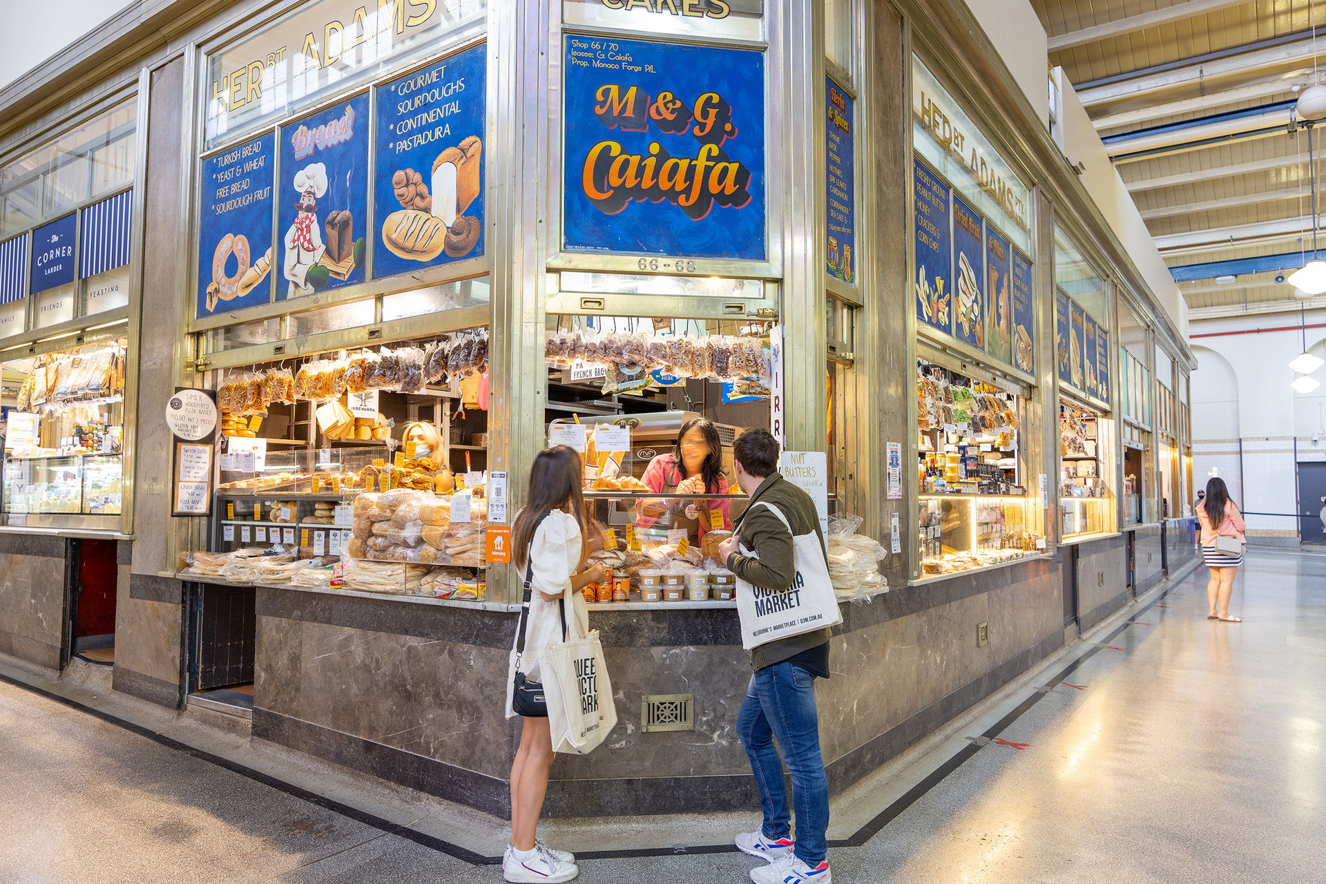 Two friends are talking to a shop keeper at a deli in a market