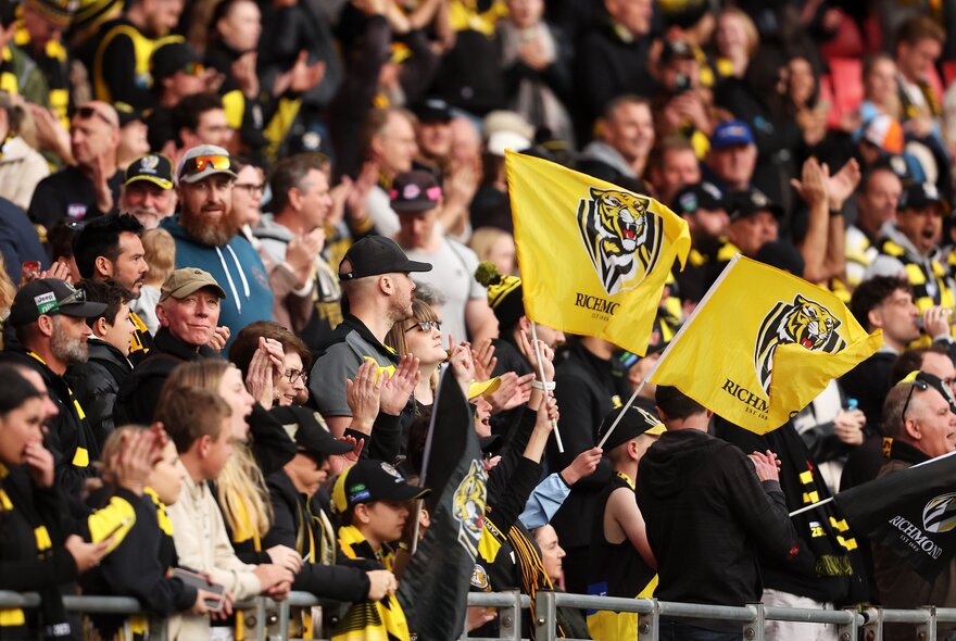 Richmond AFL football fans in the stands wearing yellow and black with banners.