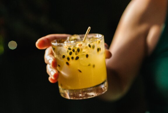 A woman's hand holding a passionfruit cocktail.