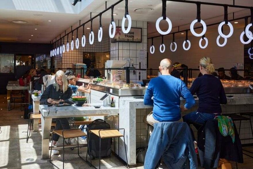 People sitting at a sushi train restaurant