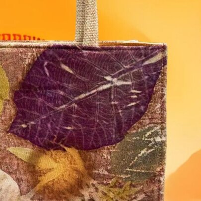 A close up of the corner of a tote bag with leaves pressed into the design. 