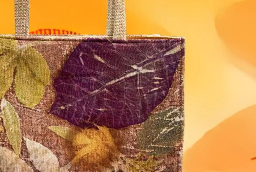 A close up of the corner of a tote bag with leaves pressed into the design. 