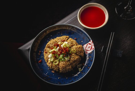 A plate of prawn toast with a red dipping sauce.