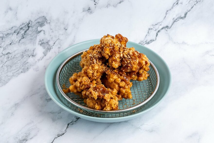 Korean fried chicken on a small blue plate.