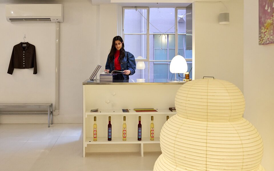 A woman browsing in a stylish home decor and fashion boutique. A giant paper lamp is in the foreground.