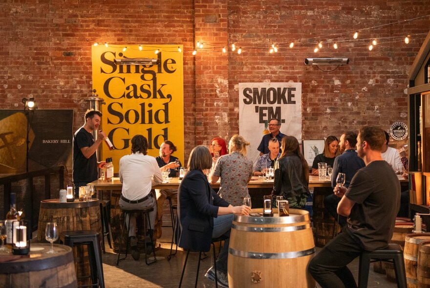People gathered around a tasting table in a distillery at an interactive tasting session.