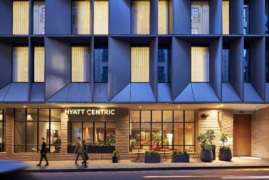 A digital render of the Hyatt Centric Hotel Melbourne, seen from across the street, with three people walking past.