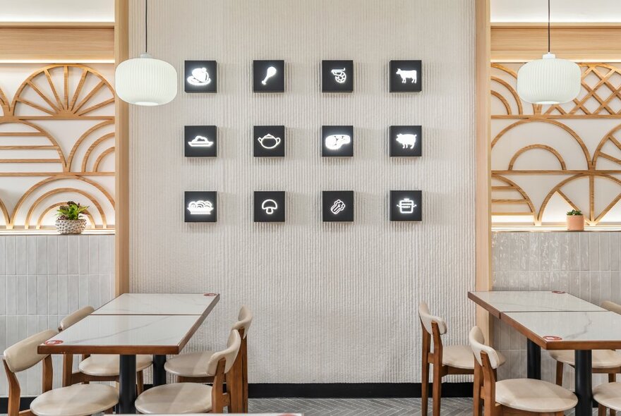 Cafe interior with wall detail depicting fans, tables and chairs, and feature wall with rows of small pictures.