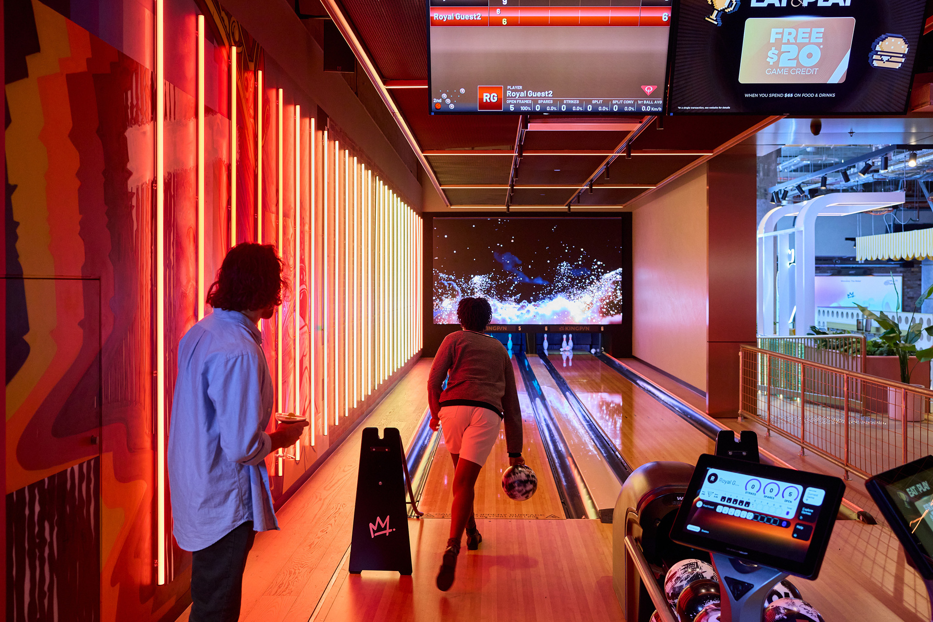 Two friends are playing ten pin bowling at a bowling alley