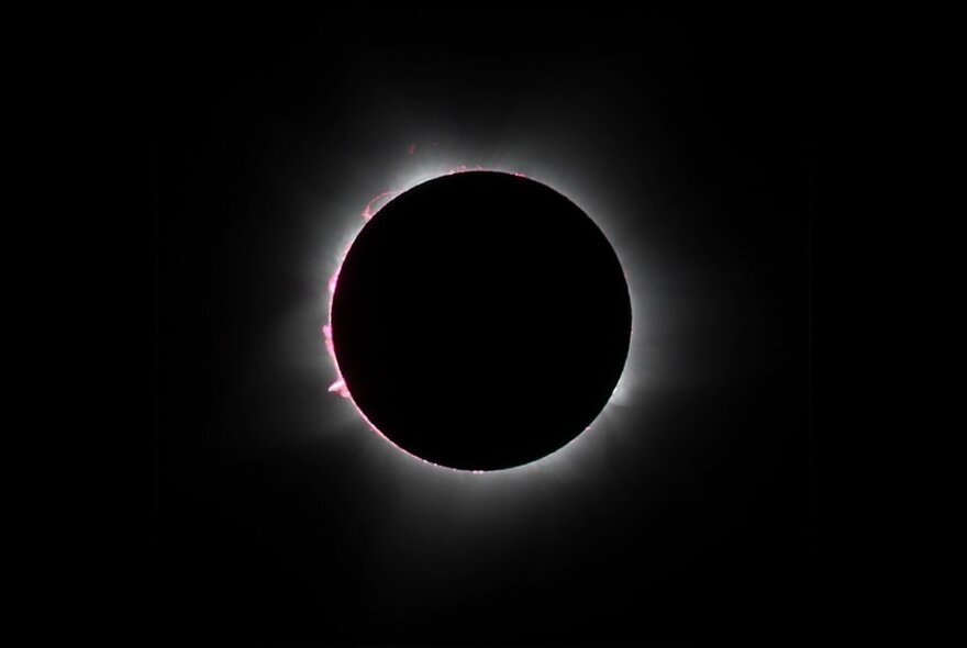 A solar eclipse, with light emerging around the edges of the blacked-out sun.