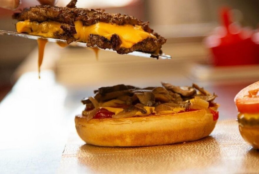 Double patty and cheese being added to a hamburger bun.