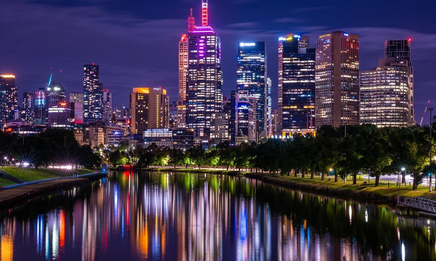 The city reflecting colourful lights over the river at night.