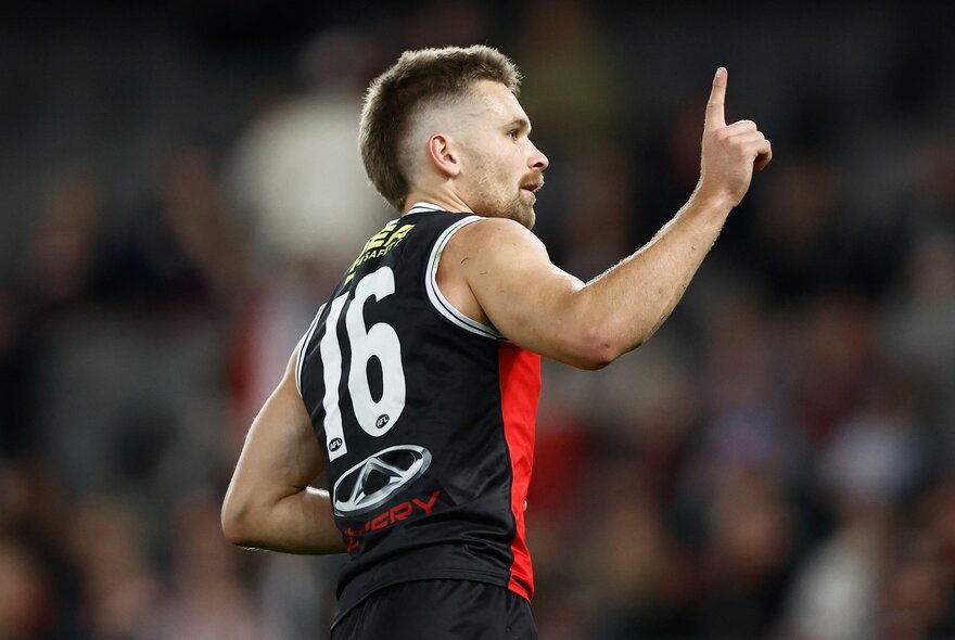 A side view of a St Kilda player holding one finger in the air during a match. 
