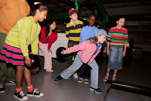A group of kids bowling at an alley.