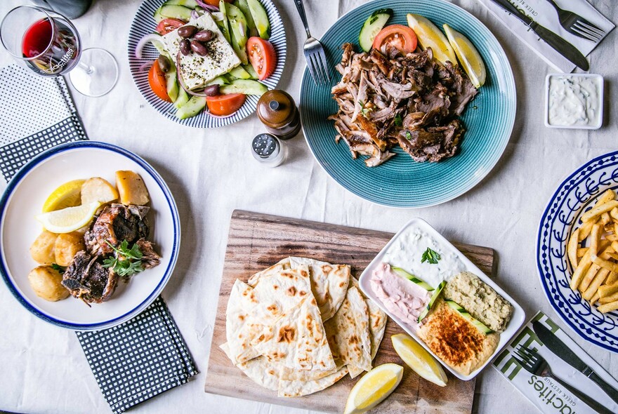 Array of dishes including bread and dips, salads and meat.