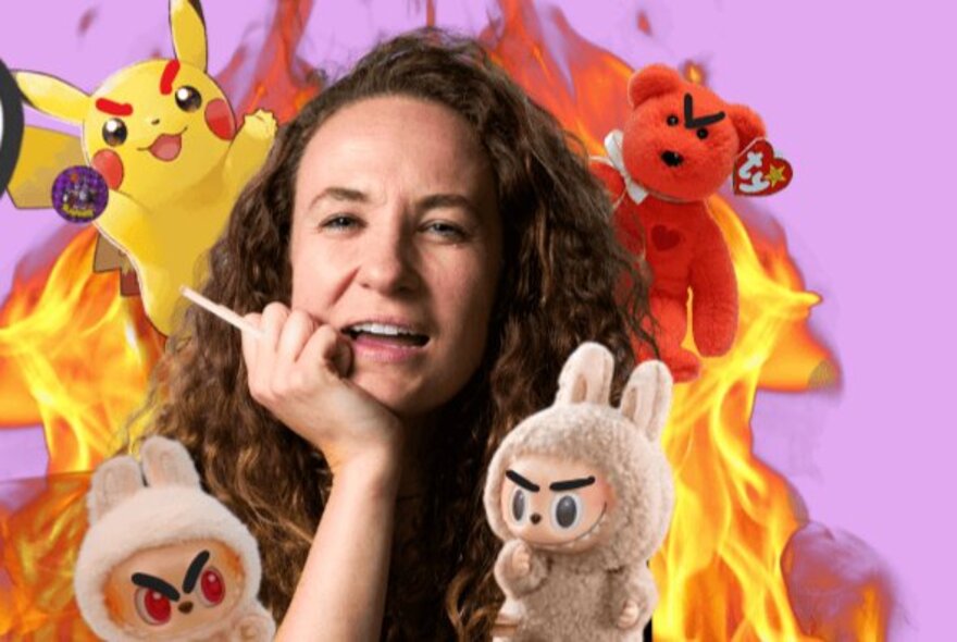 A performer with long hair and her chin resting in her hand, surrounded by soft toy fads and orange flames.
