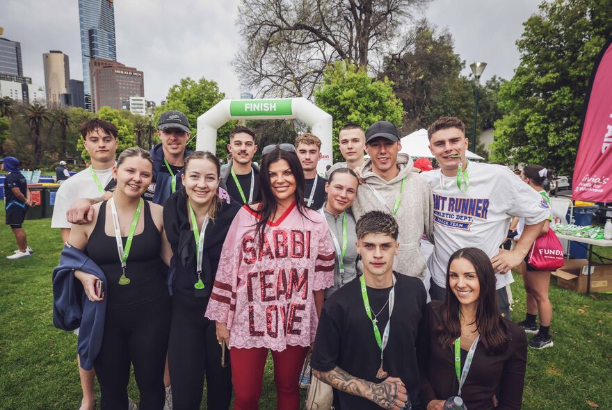 Teams celebrating having completed a charity walk, the finish line and city buildings in the background.