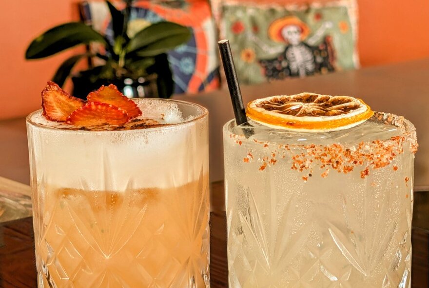Two cocktails in long glasses, both with a dried fruit garnish.