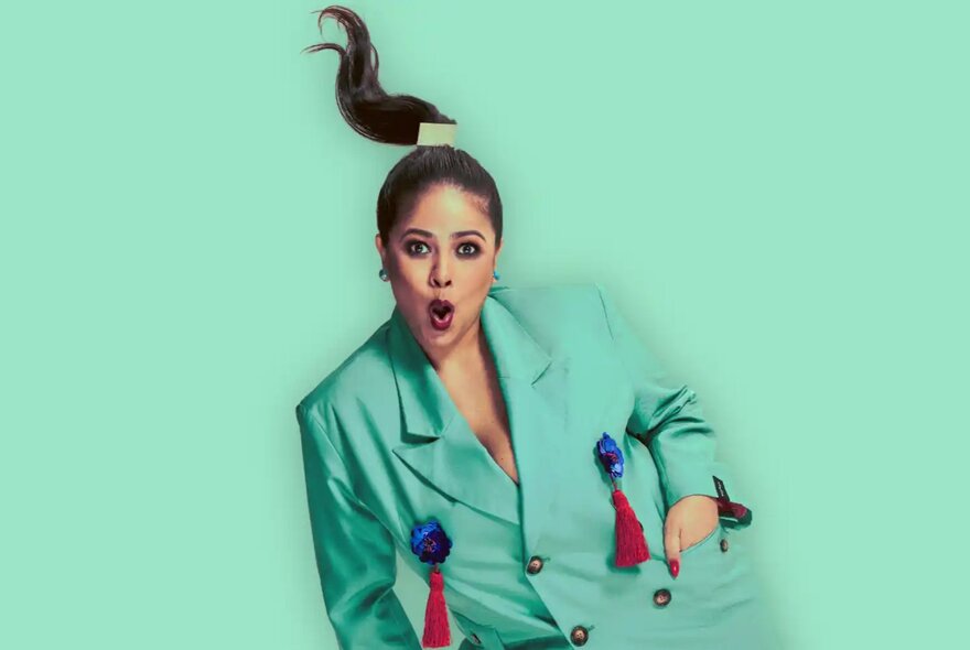 Woman with hands in her blazer pocket, hand on her knee, her pigtail flying above her head.