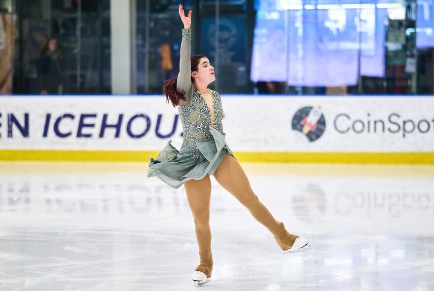 A female figure skater, skating backwards on the ice.