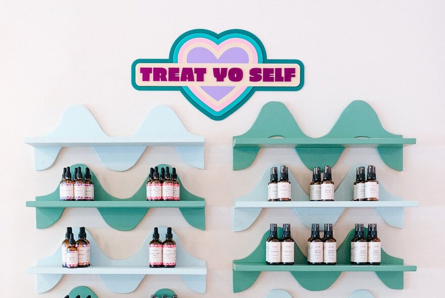 Six small wave shelves with a neat display of serum bottles, and a sign that says 'Treat Yo Self'.