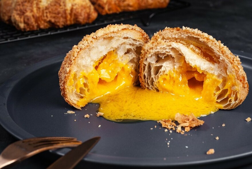 Croissant, cut in half, filled with creme, on a plate.