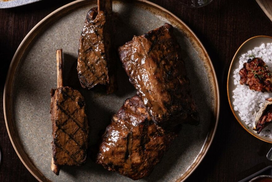 Looking down on a plate of meat that has been grilled so that a criss-cross pattern is visible. 