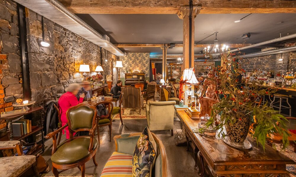 A vintage style bar with plants and antique furniture.