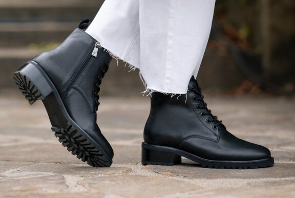 Feet modelling black lace up ankle boots with a side zipper.