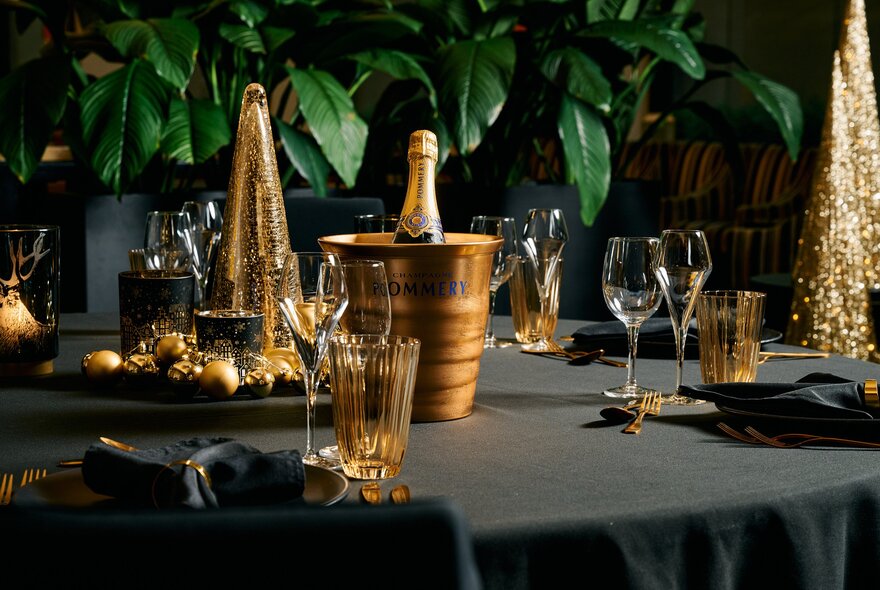 A table with a black tablecloth and champagne in an ice bucket. 