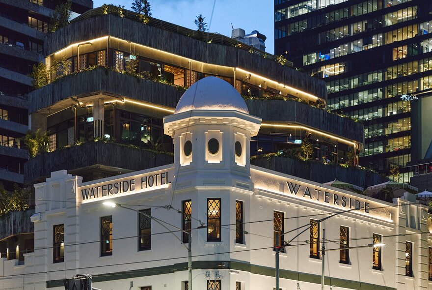 The external facade of the Waterside Hotel, with a vertical garden on the building behind it, seen from the corner.