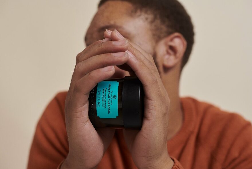 Man's hands enclosing a jar of skincare product.