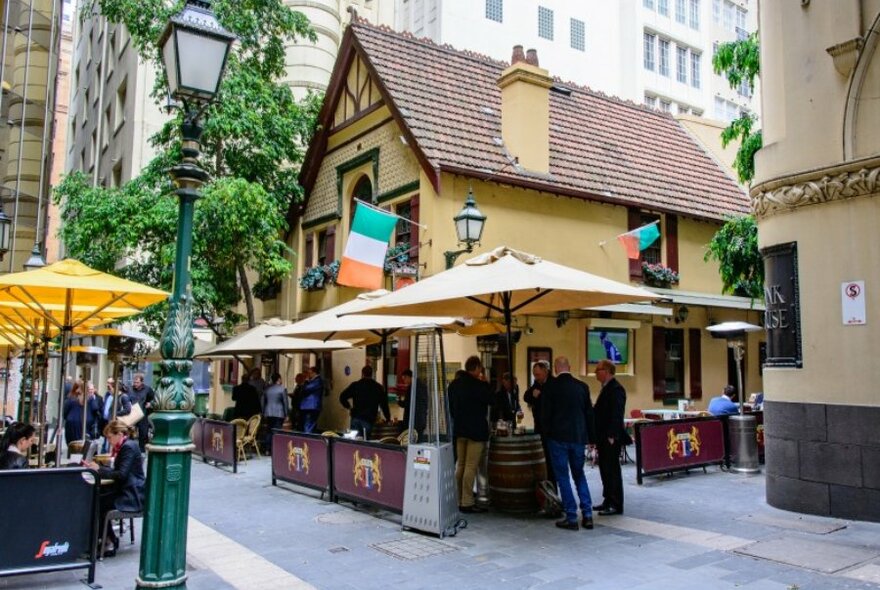 A cottage style pub with laneway dining and umbrellas set up.