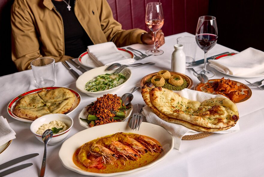 Table set with Indian food and glasses of wine