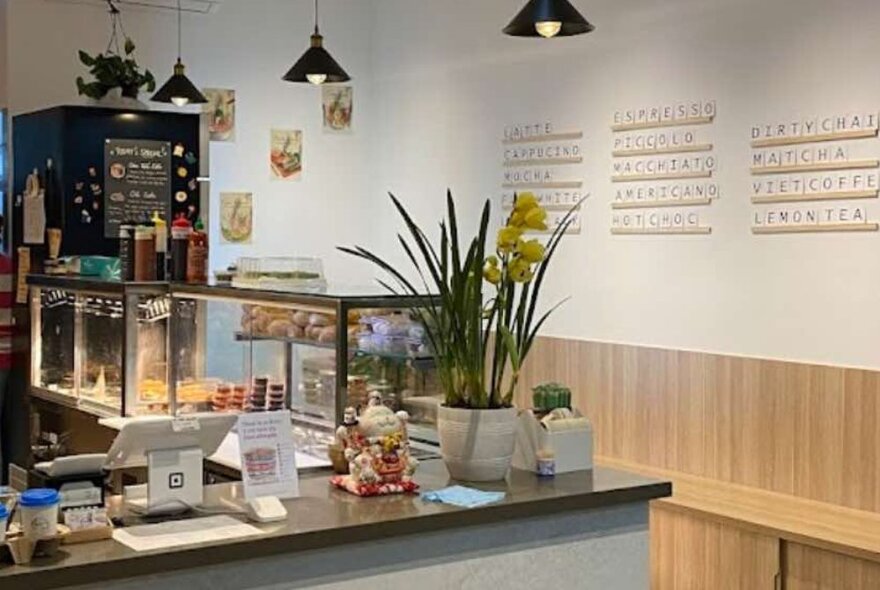 Cafe interior with counter top, display case and wooden bench seating.